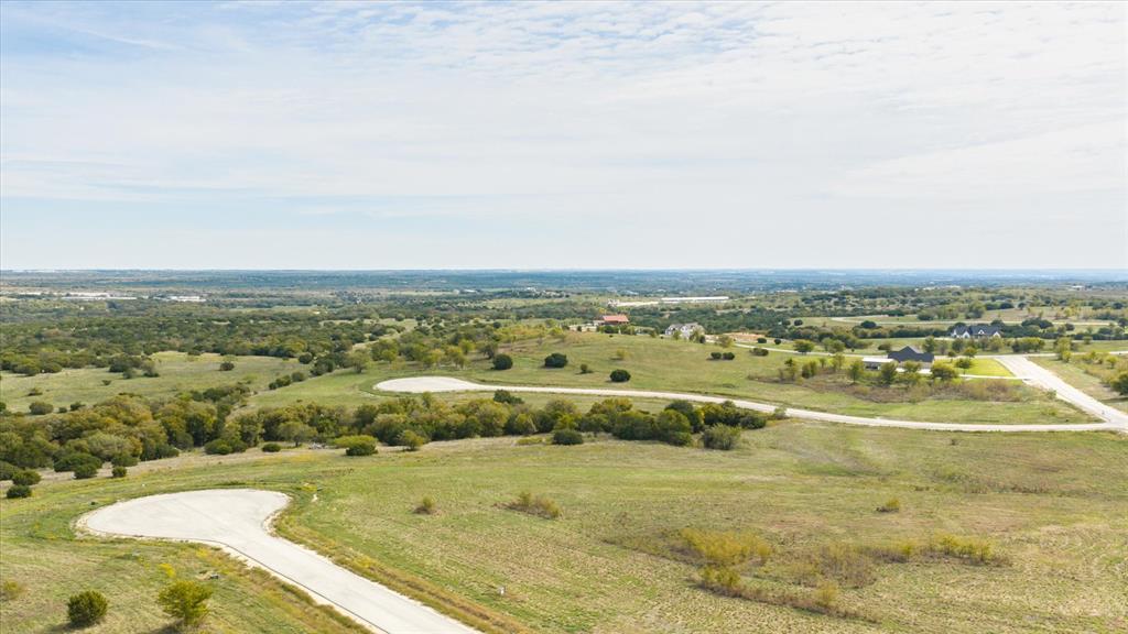 Expansive undeveloped acreage featuring rolling terrain, clusters of mature trees, paved cul-de-sacs, and wide-reaching territorial horizons