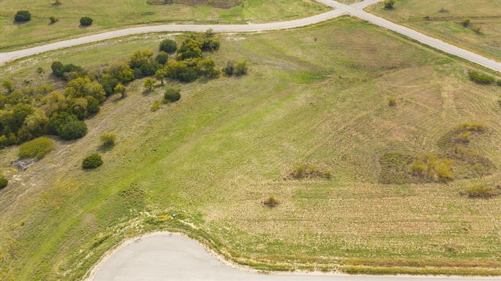 Expansive undeveloped acreage featuring topography variations, clusters of mature trees, and direct paved road frontage