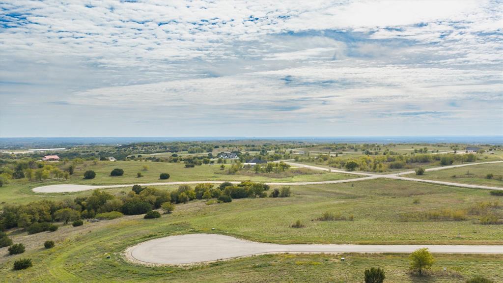 Elevated land parcel featuring rolling topography, native vegetation, scattered mature trees, and paved cul-de-sac infrastructure