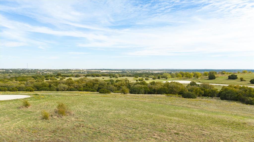 Expansive acreage featuring rolling terrain, clusters of mature trees, and a horizon backdrop