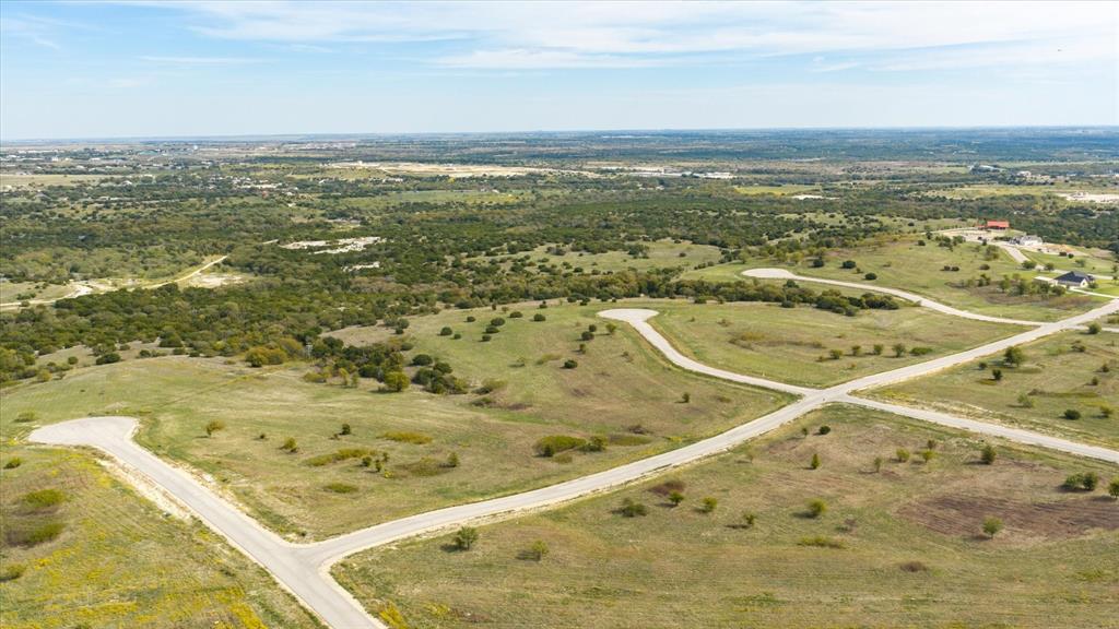 Aerial perspective of expansive undeveloped land featuring rolling topography, paved cul-de-sacs, and mature native vegetation