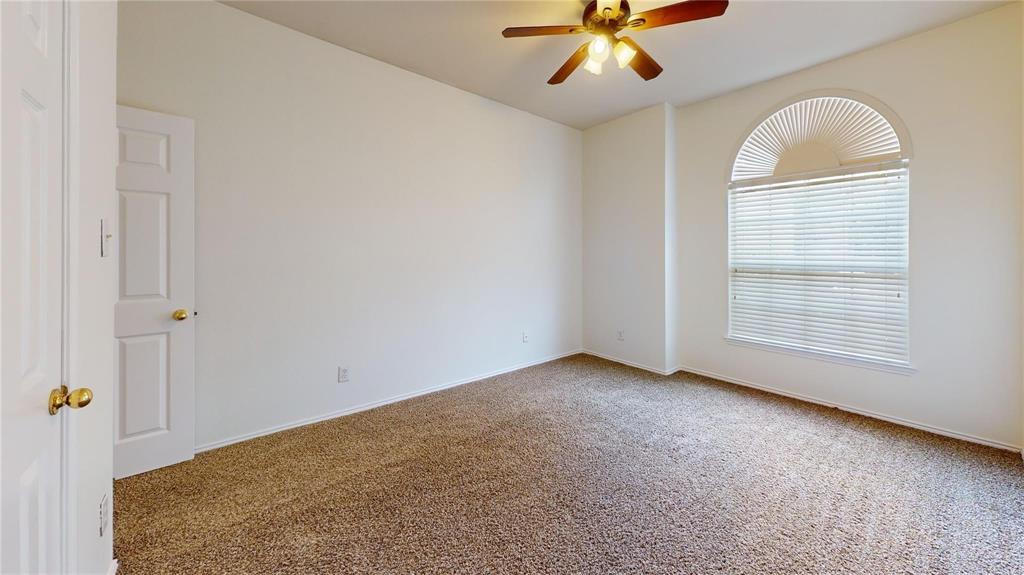 Room featuring neutral carpeting, an arched window with horizontal blinds, and a central ceiling fan with integrated lighting
