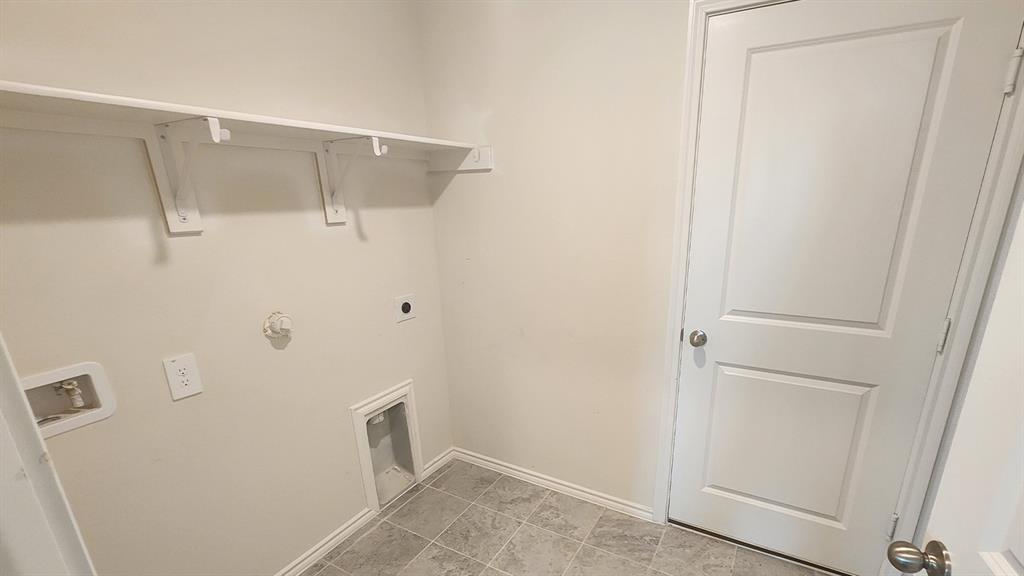 Integrated shelving system, white interior door, tiled flooring, neutral wall tones, and utility hookups