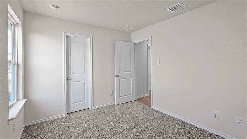 Neutral interior space featuring neutral-toned carpeting, two-panel interior doors, and a window with a sill