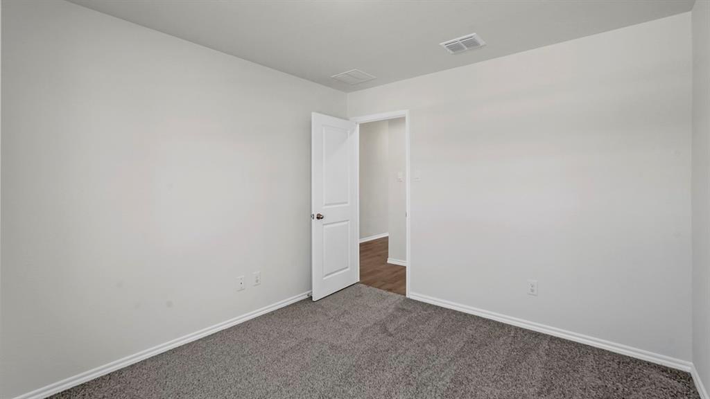 Neutral interior featuring grey carpeting, crisp white walls, and a white paneled door