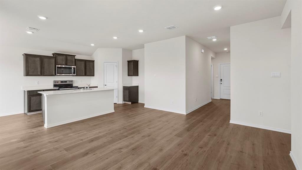 Open-concept kitchen featuring dark-finish cabinetry, white countertops, a central island, recessed lighting, and wood-finish flooring