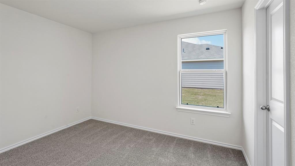 Neutral wall paint, carpeted flooring, single-hung window with a sill, and a multi-panel door with a round knob