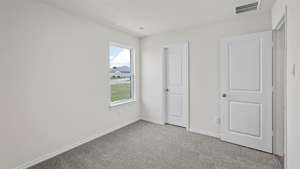 Neutral interior featuring textured carpeting, single-hung window, and two-panel interior doors