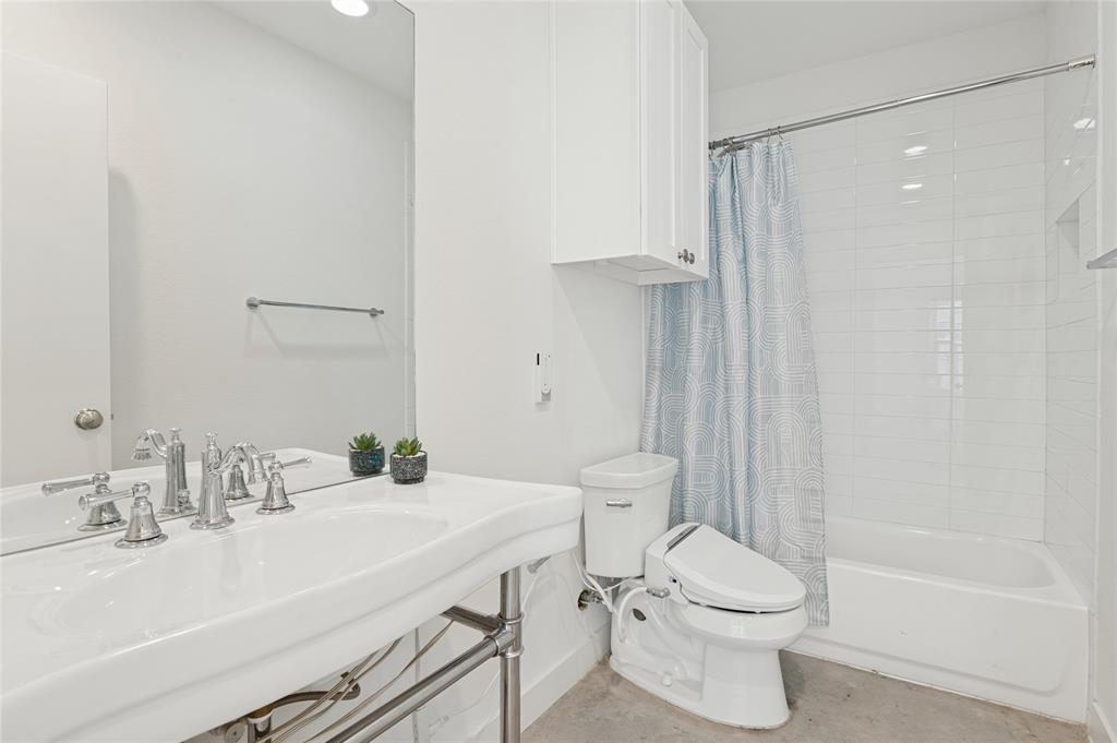 Bathroom featuring a wall-mounted vanity with a porcelain sink, polished metal faucet, white shaker-style wall cabinetry, and a shower-tub combination with subway tile surround