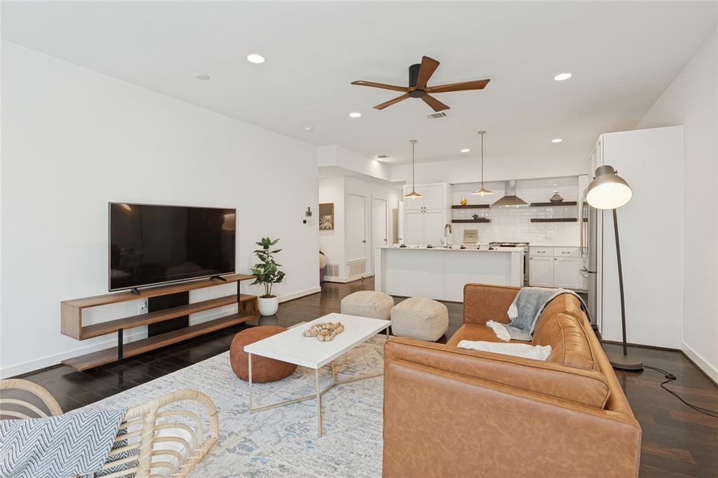 Open-concept living space featuring wood-finish flooring, recessed lighting, a ceiling fan, and a kitchen island with pendant lighting