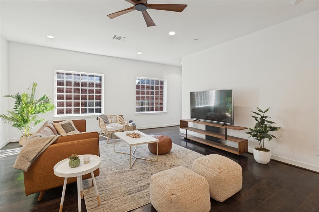 Dark wood-finish flooring, recessed lighting, grid-pattern windows, and a ceiling fan