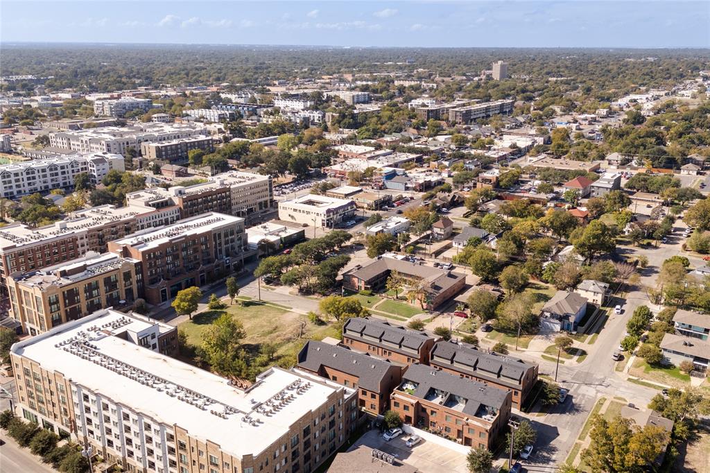 Aerial perspective of an urban neighborhood featuring multi-story residential buildings, paved street grids, and mature trees
