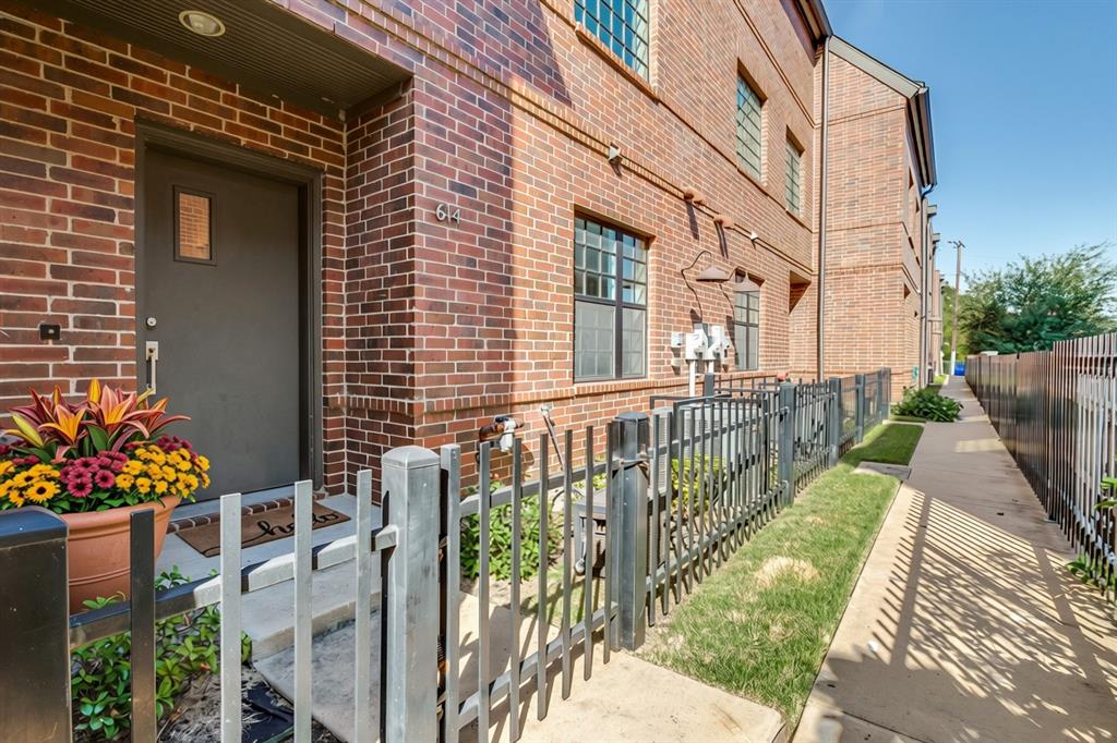 Red brick exterior, metal entry door, multi-pane windows, and fenced front entryway