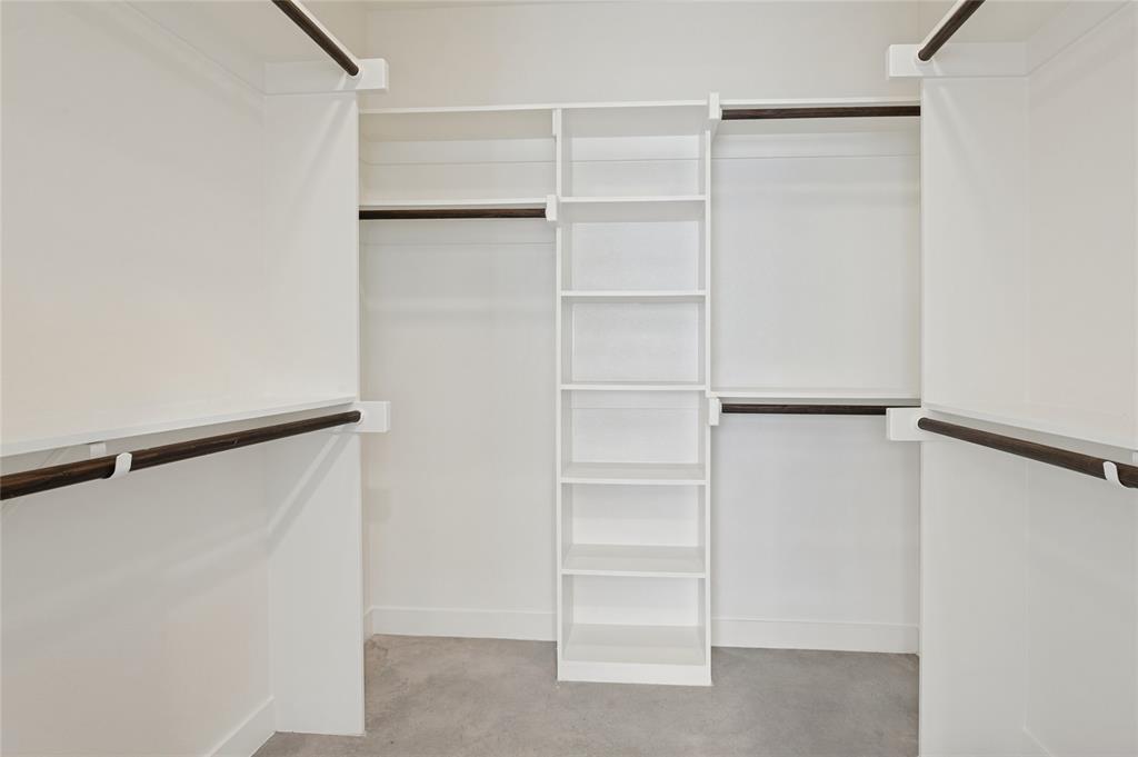 Walk-in closet featuring white built-in shelving, multiple tiers of hanging rods, and neutral flooring