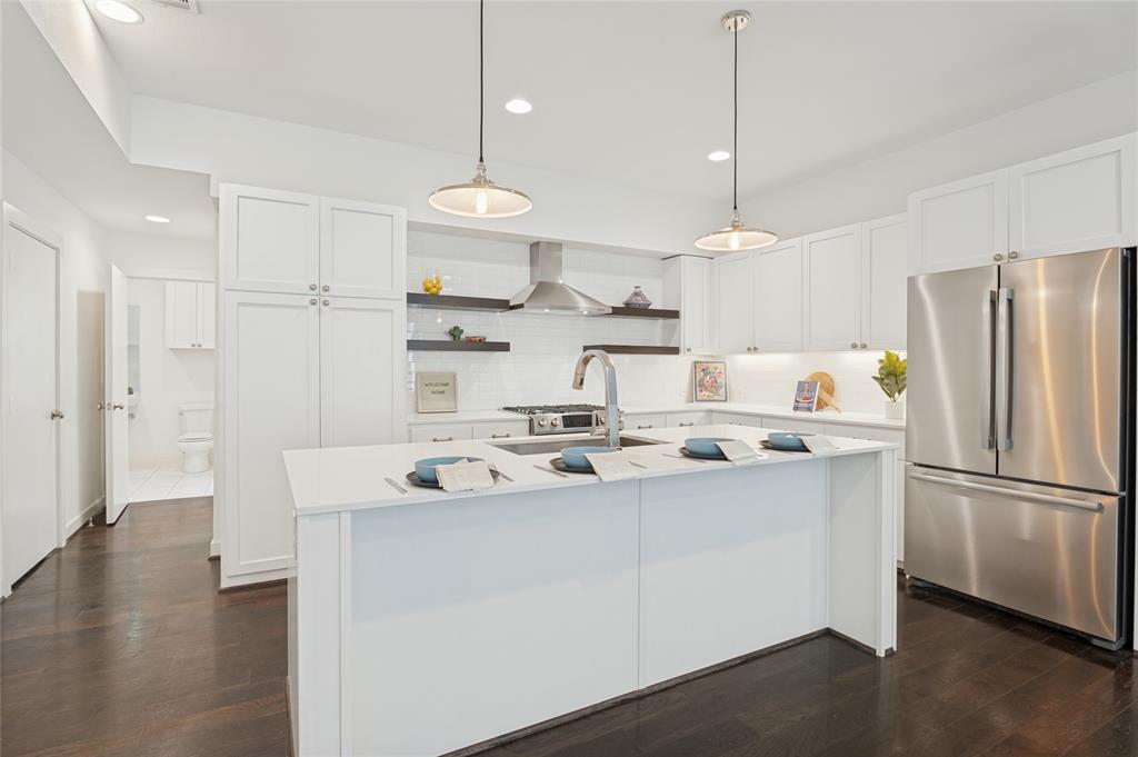 Kitchen featuring white cabinetry, quartz countertops, stainless steel appliances, dark wood-finish flooring, and dual hanging pendant lights