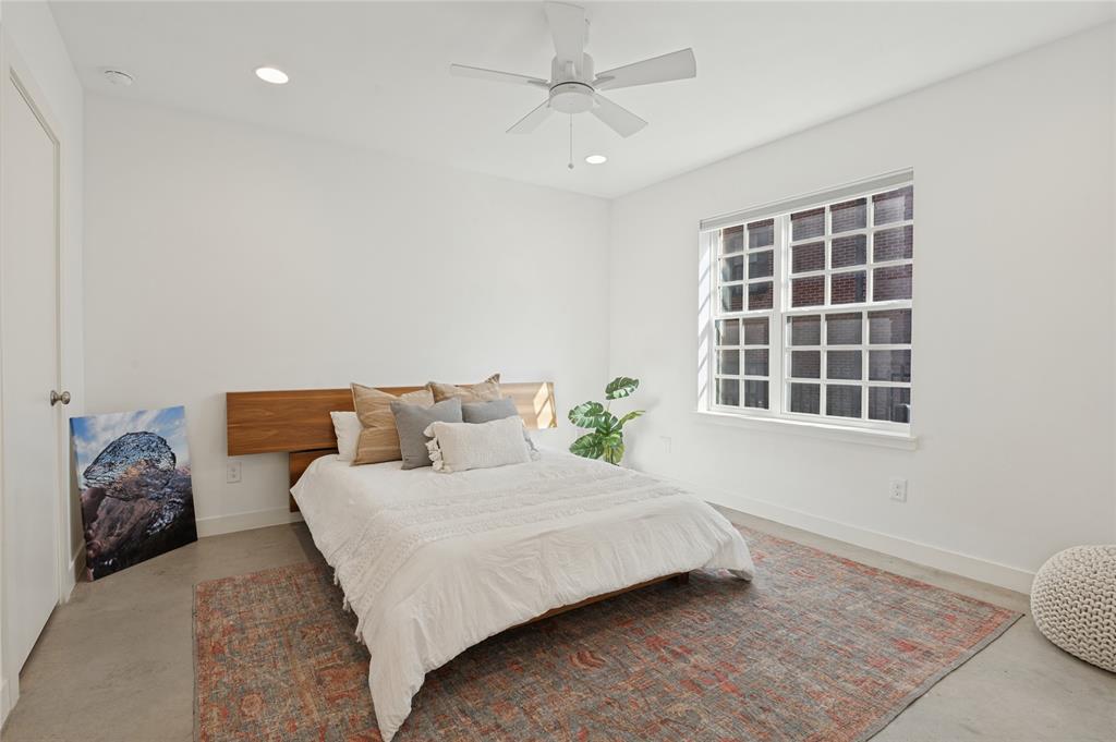Polished concrete flooring, recessed lighting, white multi-pane window, and a built-in horizontal wood-finish headboard