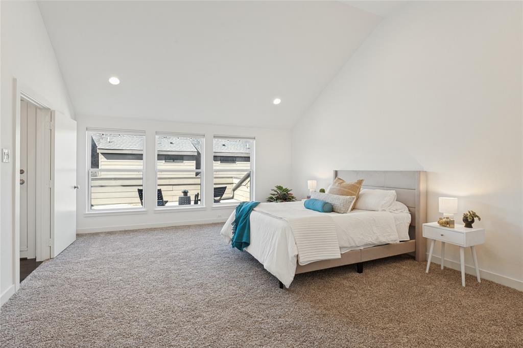 Vaulted ceiling, neutral wall tones, wall-to-wall carpeting, and large multi-pane windows