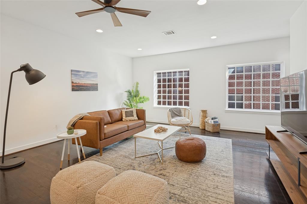 Living area featuring dark-stained wood-finish flooring, recessed lighting, grid-pattern windows, and a ceiling fan