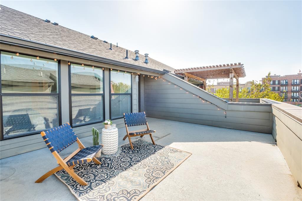 Expansive rooftop terrace featuring horizontal wood-style siding, a wooden pergola, and large picture windows