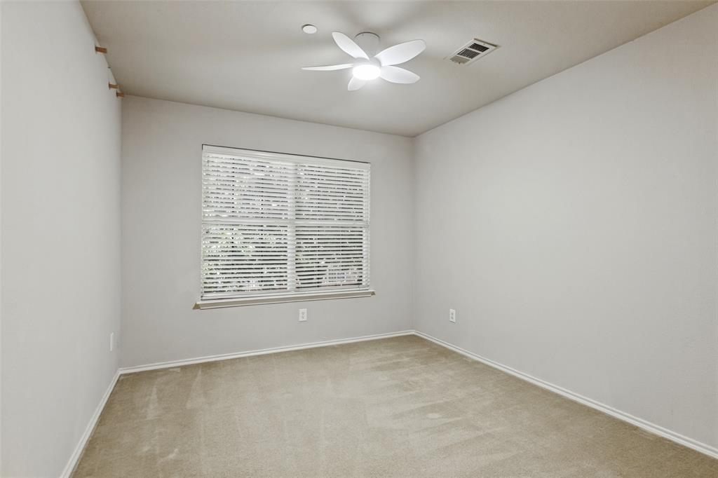 Neutral interior space featuring carpeted flooring, a multi-blade ceiling fan with integrated lighting, and a large window fitted with horizontal blinds