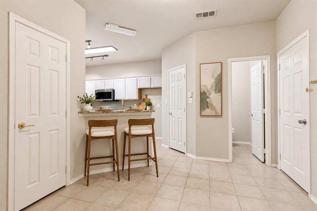 Kitchen featuring white cabinetry, a breakfast bar with a stone countertop, and tile flooring throughout the area