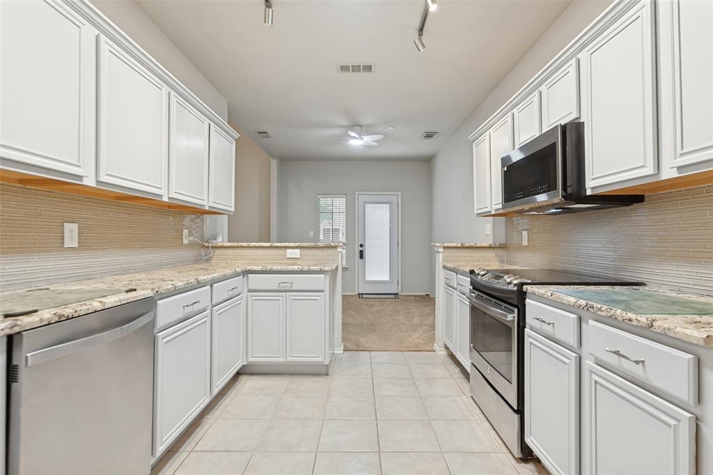 Kitchen featuring white shaker-style cabinetry, stone-finish countertops, tile backsplash, and stainless steel appliances