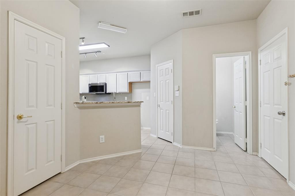 Interior area featuring neutral-toned tile flooring, multi-panel doors, and an open kitchen counter with stone-finish surfaces