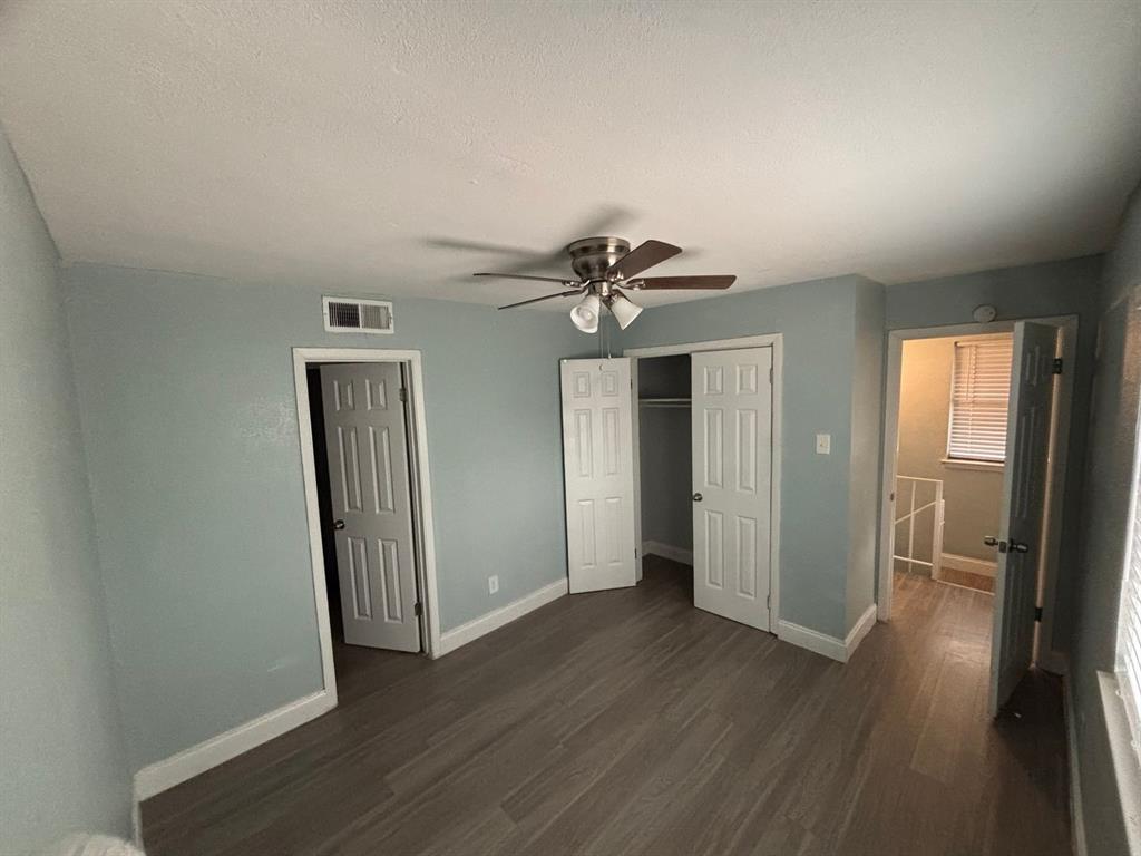 Wood-finish flooring, six-panel interior doors, and a ceiling-mounted light fixture with a fan
