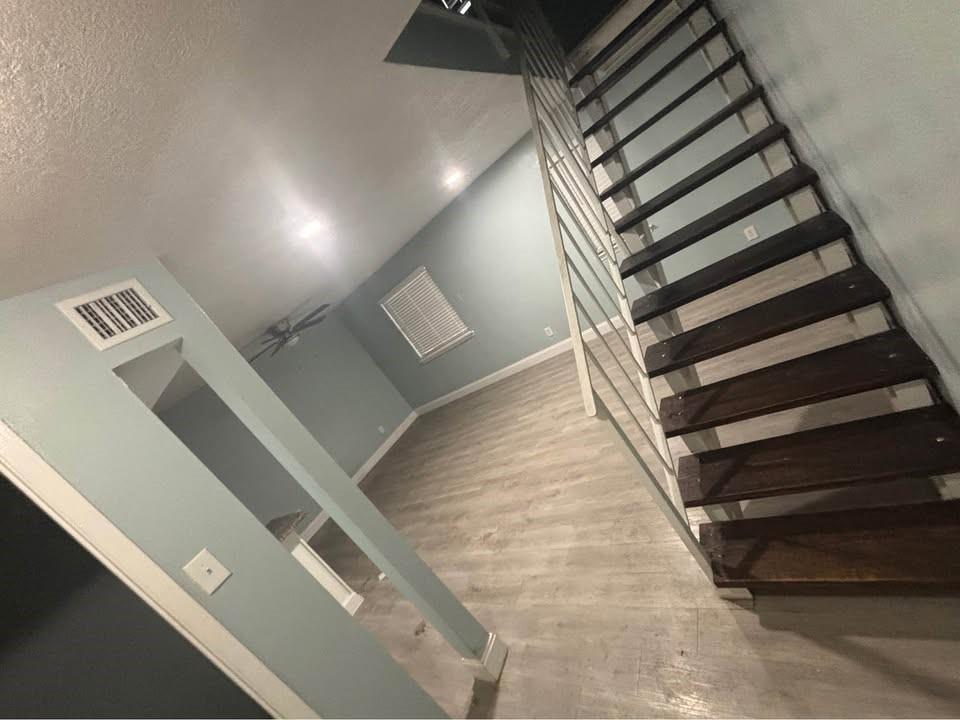 Open-tread staircase with metal railing, wood-finish flooring, and recessed ceiling lighting