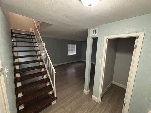 Staircase with wooden treads and white metal railing, wood-finish flooring, and recessed ceiling lighting