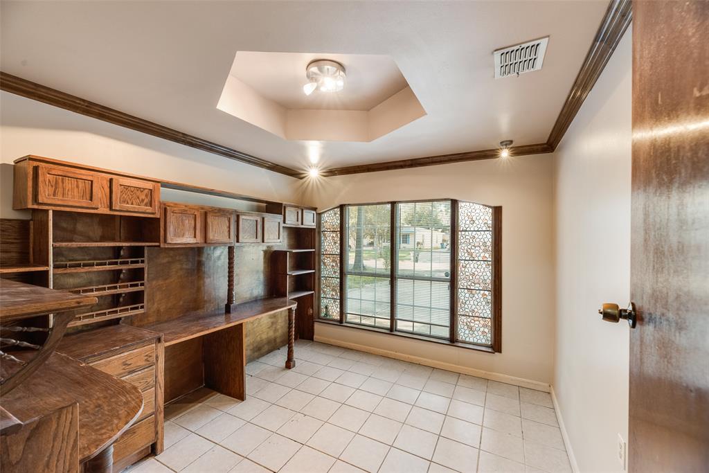 Built-in wood cabinetry with integrated desk surface, hexagonal tray ceiling, ceramic tile flooring, and decorative lattice-patterned window side panels