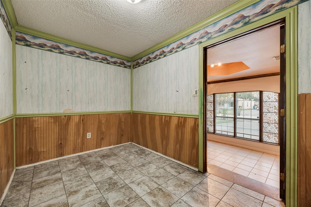 Interior space featuring stone-style tile flooring, wood-paneled wainscoting, and decorative wallpaper borders with painted wood trim