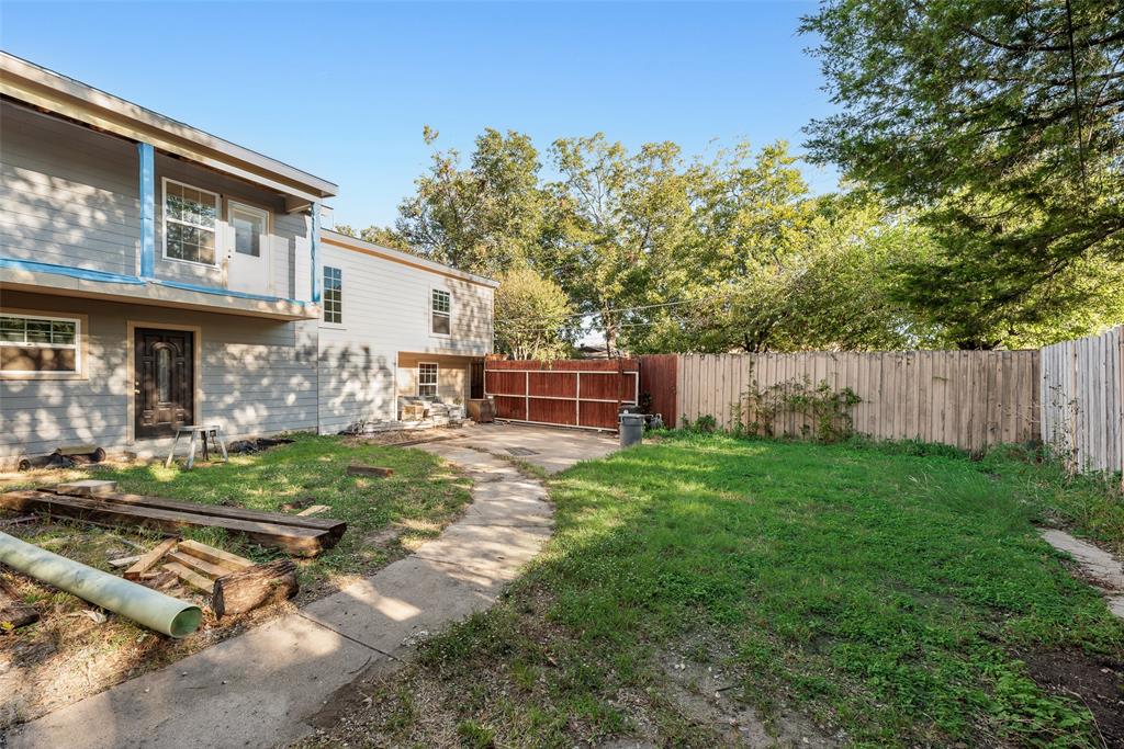 Rear yard featuring a concrete patio path, wood-panel exterior siding, and perimeter wood fencing