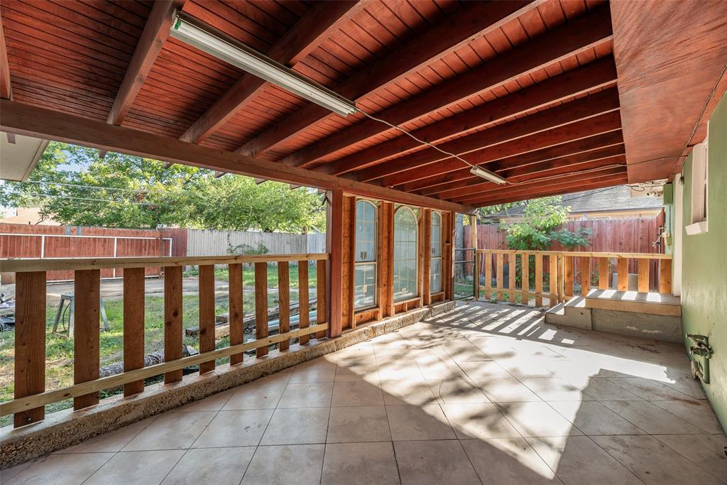Covered patio featuring a timber-beamed ceiling, tile flooring, and wood railing