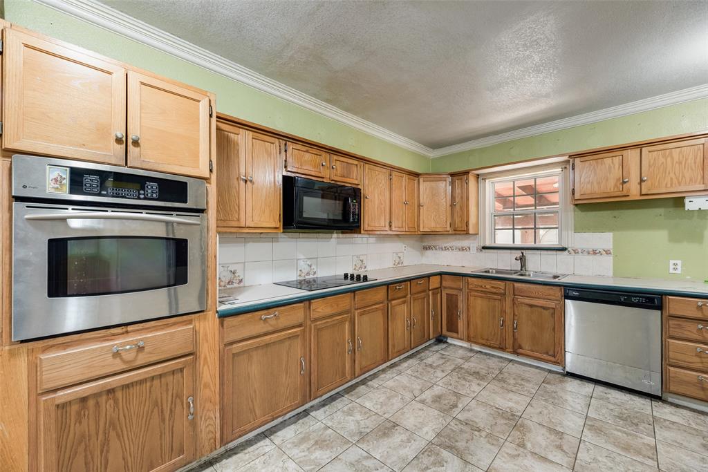 Kitchen featuring light-finish wood cabinetry, stainless steel built-in oven, integrated microwave, stainless steel dishwasher, and ceramic tile flooring