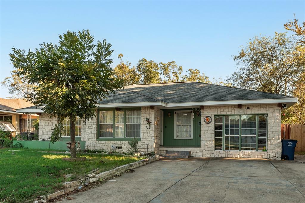 Stone exterior facade with a low-pitched roof, multi-pane windows, and a concrete driveway