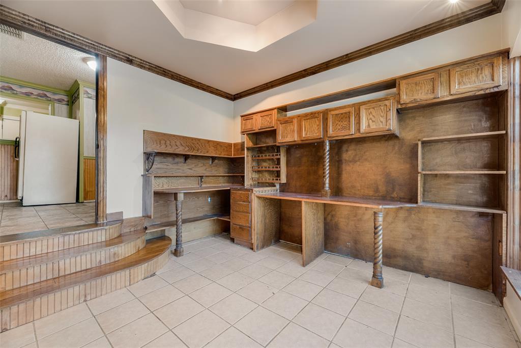 Custom built-in wood cabinetry, integrated desk workspace, coffered ceiling detail, and wood-trimmed steps