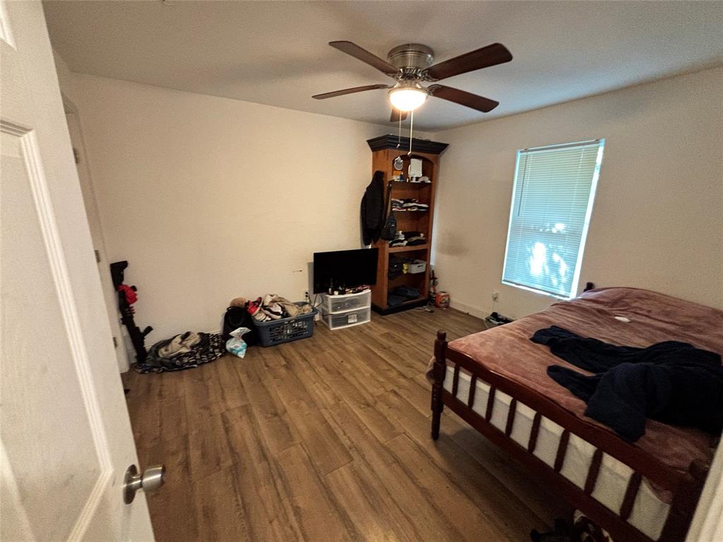 Wood-finish flooring, ceiling fan with integrated light fixture, and built-in corner shelving unit