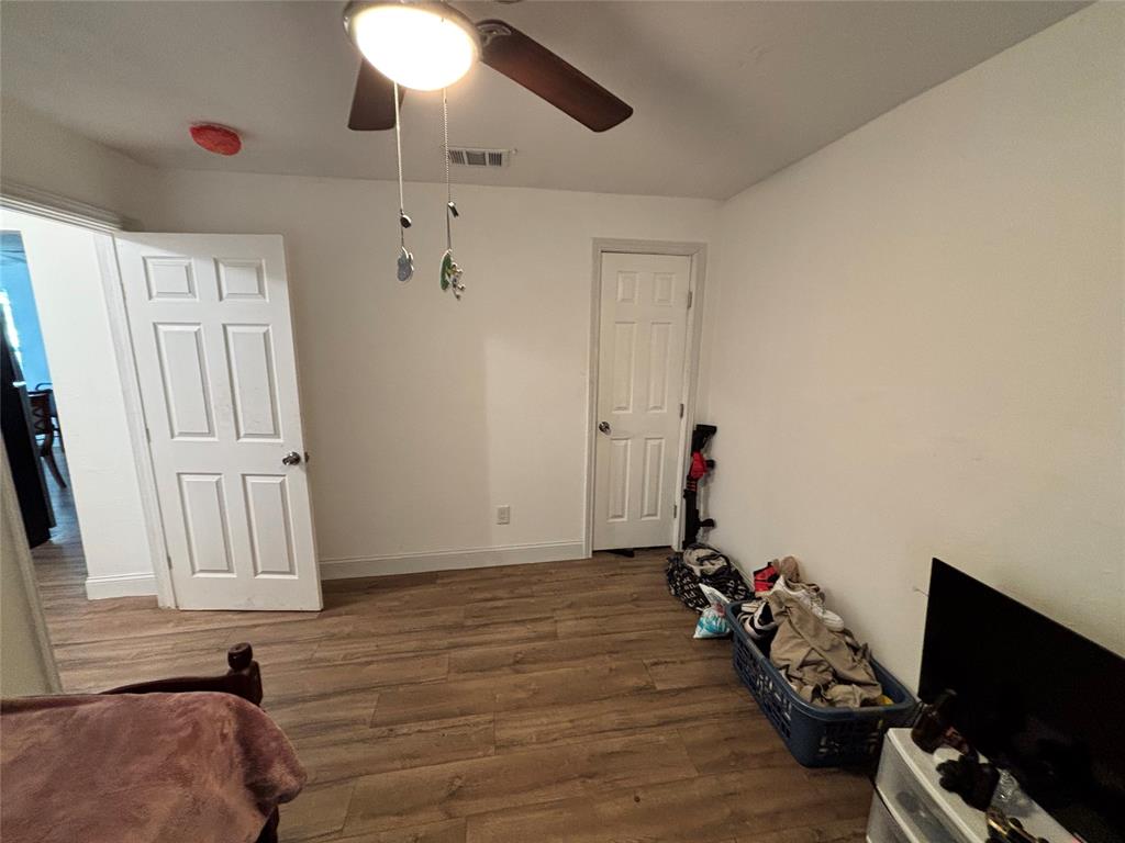 Wood-finish flooring, six-panel interior doors, and a ceiling-mounted light fixture with integrated fan