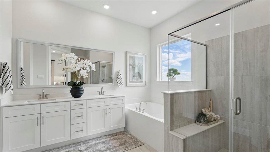 Double vanity with white cabinetry, large-format tiled shower with a glass enclosure, soaking tub, and polished metal fixtures