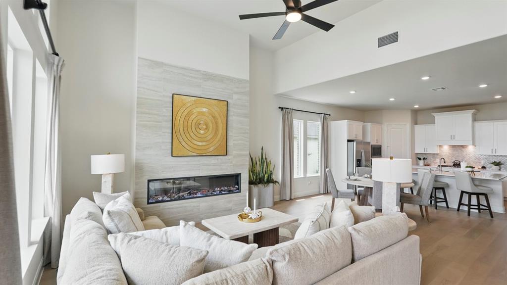 High ceilings, stone-finish fireplace surround with linear firebox, wood-finish flooring, and recessed lighting