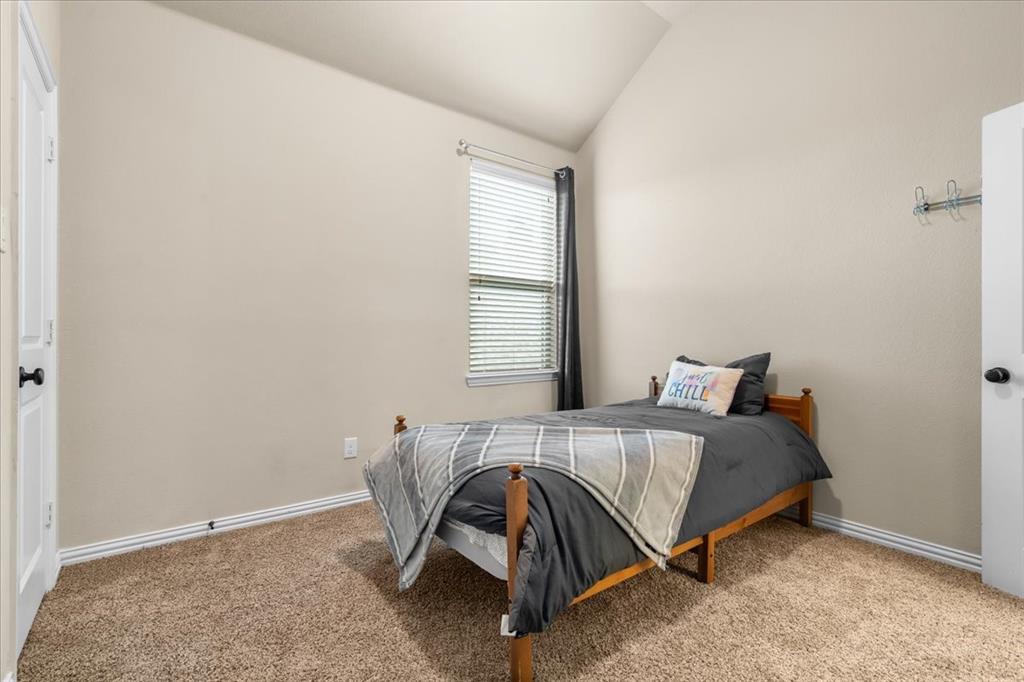 Vaulted ceiling, neutral wall tones, wall-to-wall carpeting, single-panel interior doors, and a window with horizontal blinds