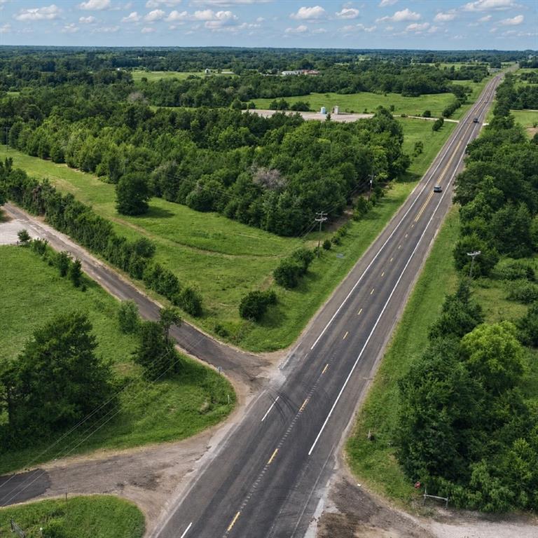 Expansive acreage featuring cleared grassy fields, mature tree lines, and paved road access