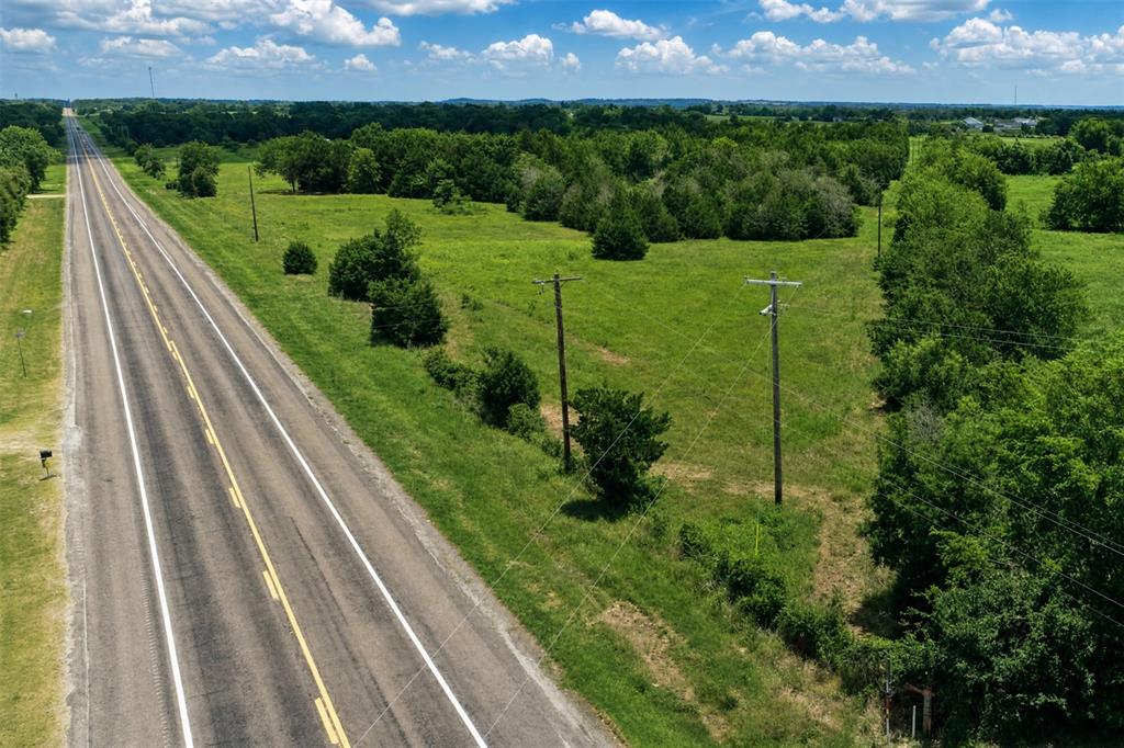 Expansive acreage featuring mature trees, native grasses, and paved road frontage