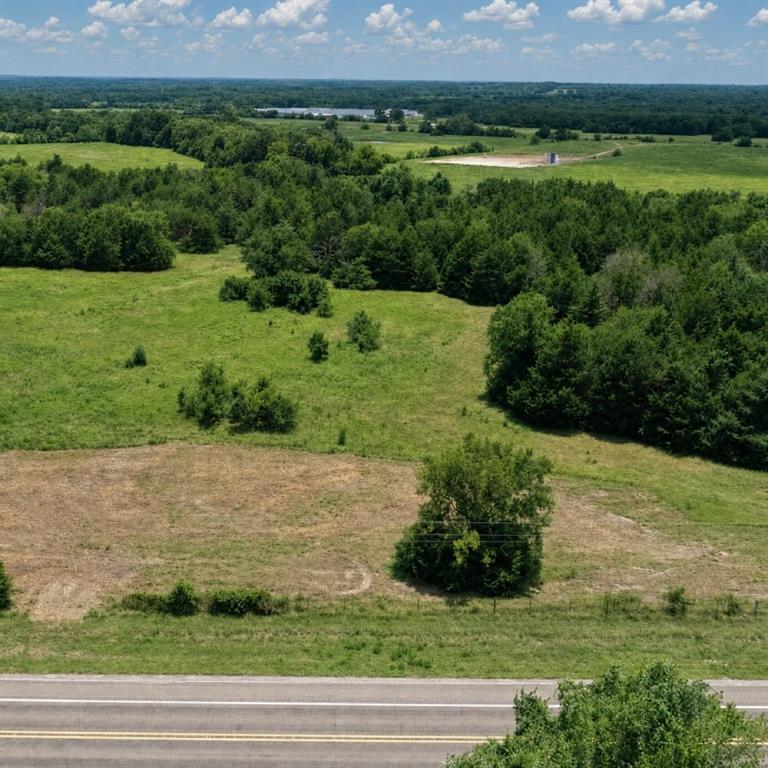 Expansive acreage featuring cleared pasture, mature tree lines, and paved road frontage