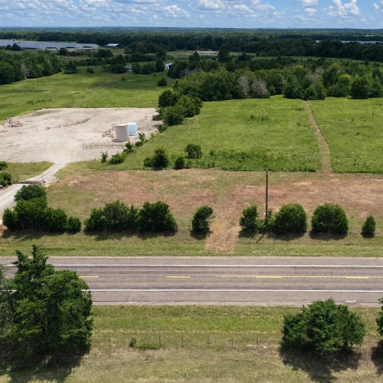 Expansive acreage featuring cleared level terrain, mature tree lines, and paved road frontage