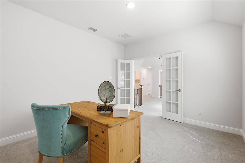 Vaulted ceiling with neutral carpeting and glass-paned French doors