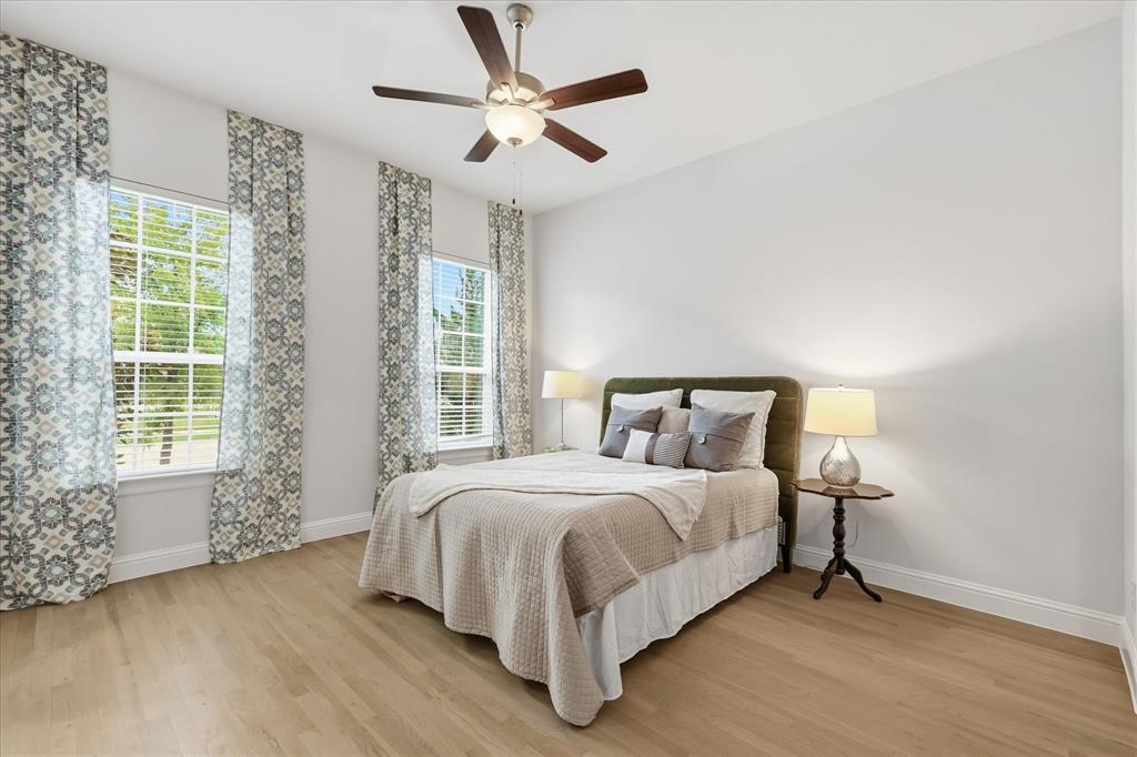 Light-filled room featuring wood-finish flooring, dual windows, and a central ceiling fan with an integrated light fixture