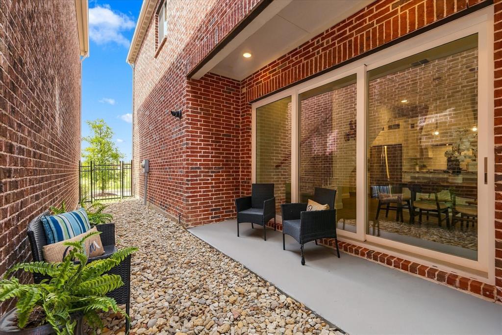 Red brick exterior featuring a covered patio, concrete flooring, sliding glass door, and gravel landscaping