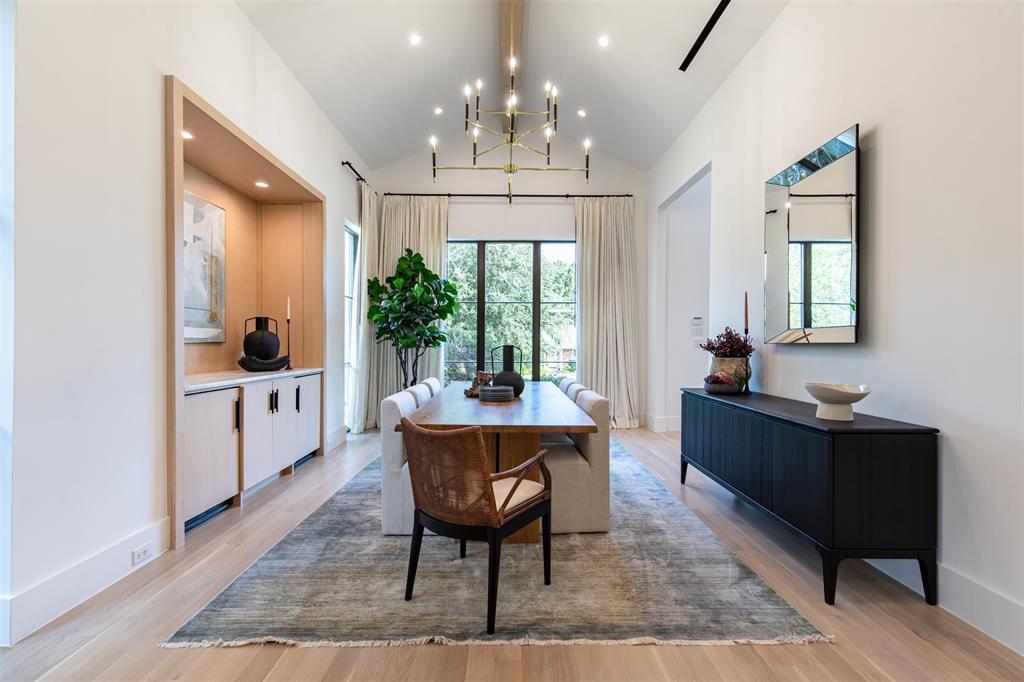 Vaulted ceiling featuring a central exposed beam, recessed lighting, brass multi-arm chandelier, built-in recessed cabinetry with light-finish millwork, and wood-finish flooring
